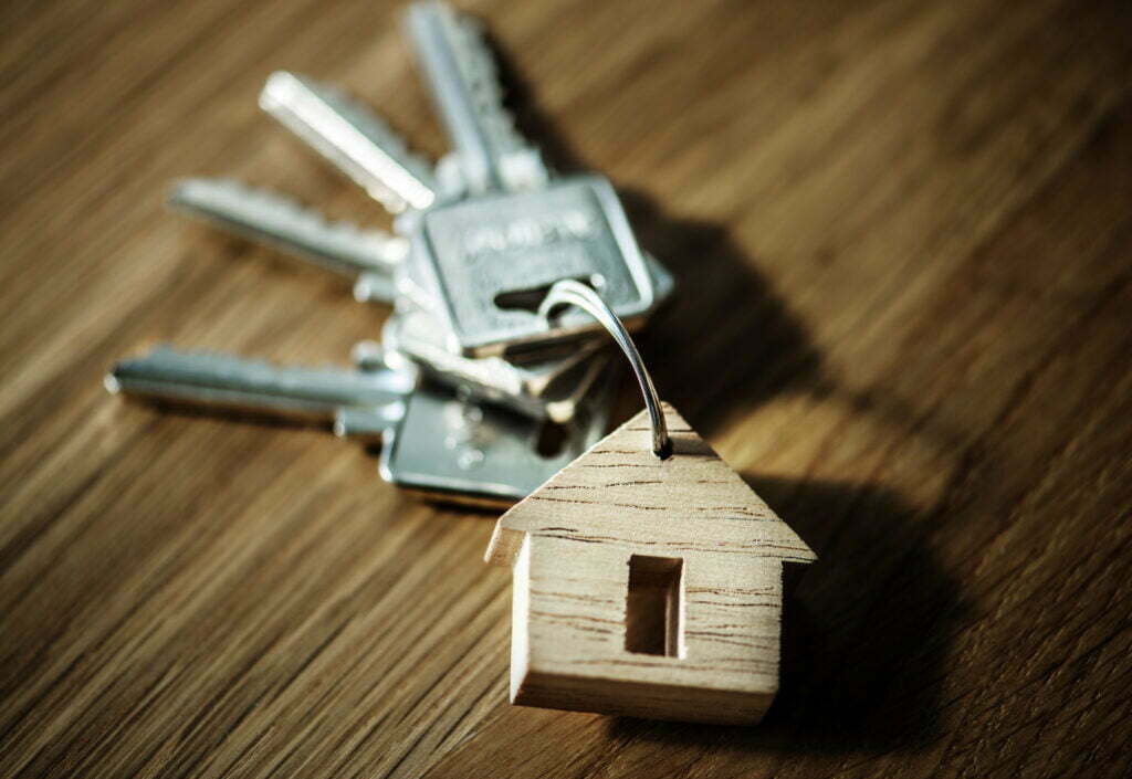 Keys and house charm representing new homeownership and home improvement tips.