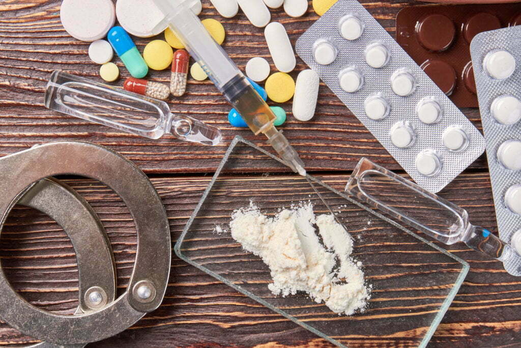 Pills, syringes, handcuffs, and drug paraphernalia illustrating overcoming drug addiction and self-care.